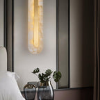 Clérachic Selvia wall light lit beside a bed with a black window frame and glass vases.