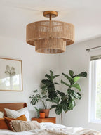 Near a fiddle-leaf fig and framed prints, this Clérachic flush-mount glows above a bedroom in gold hardware.