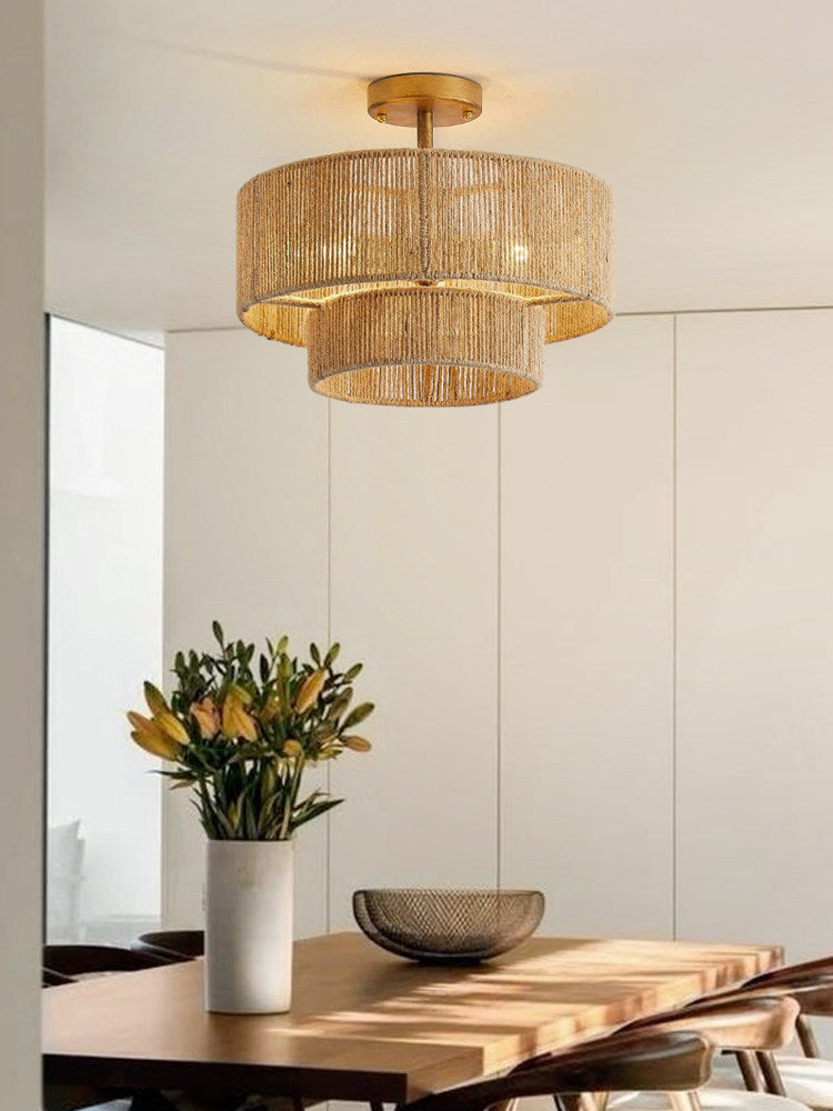 In a sunlit dining nook with a vase of flowers, this Clérachic light glows through its rope tiers in gold hardware.
