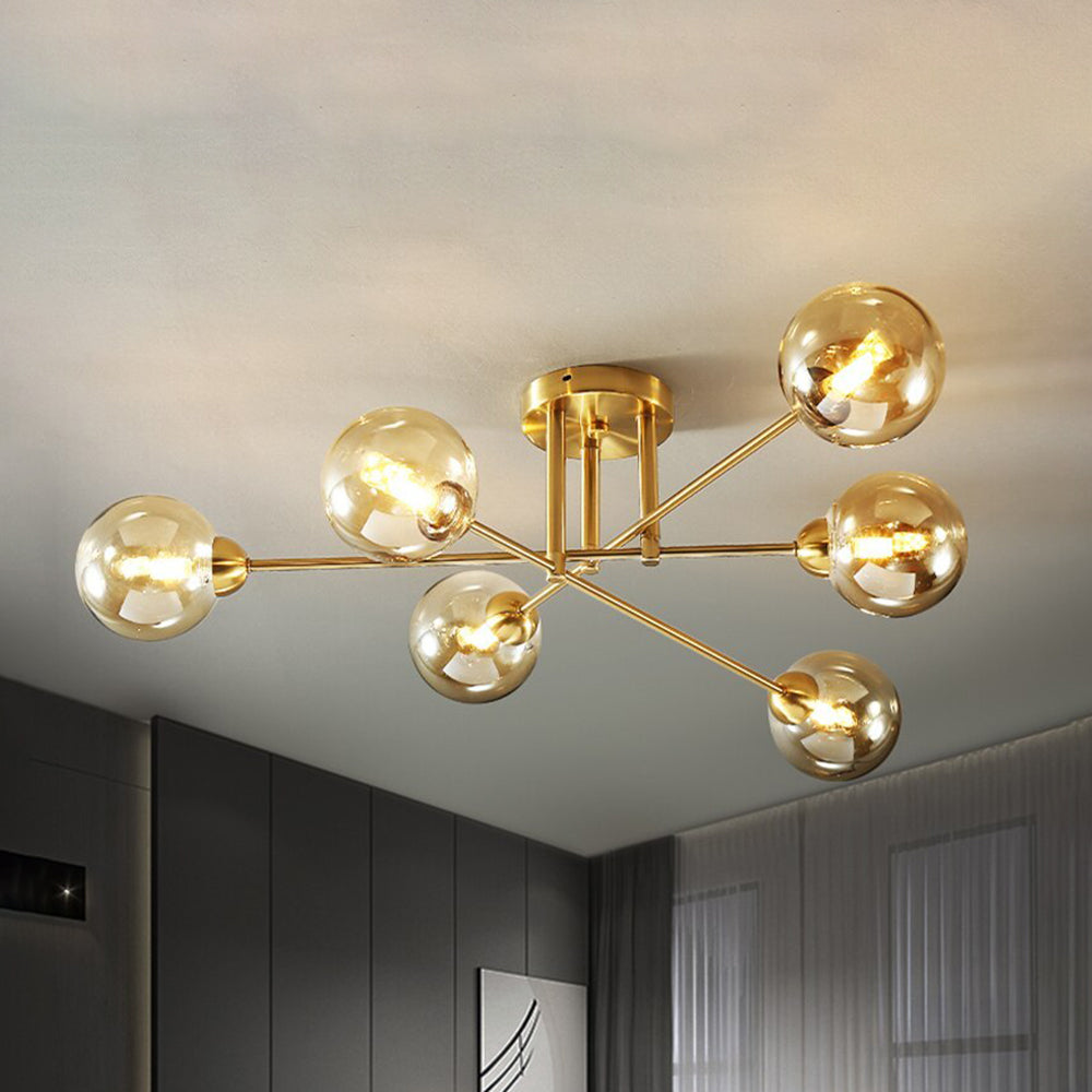 Clérachic sputnik chandelier in gold with six cognac globes, lit above a grey-panelled living room with a framed print.