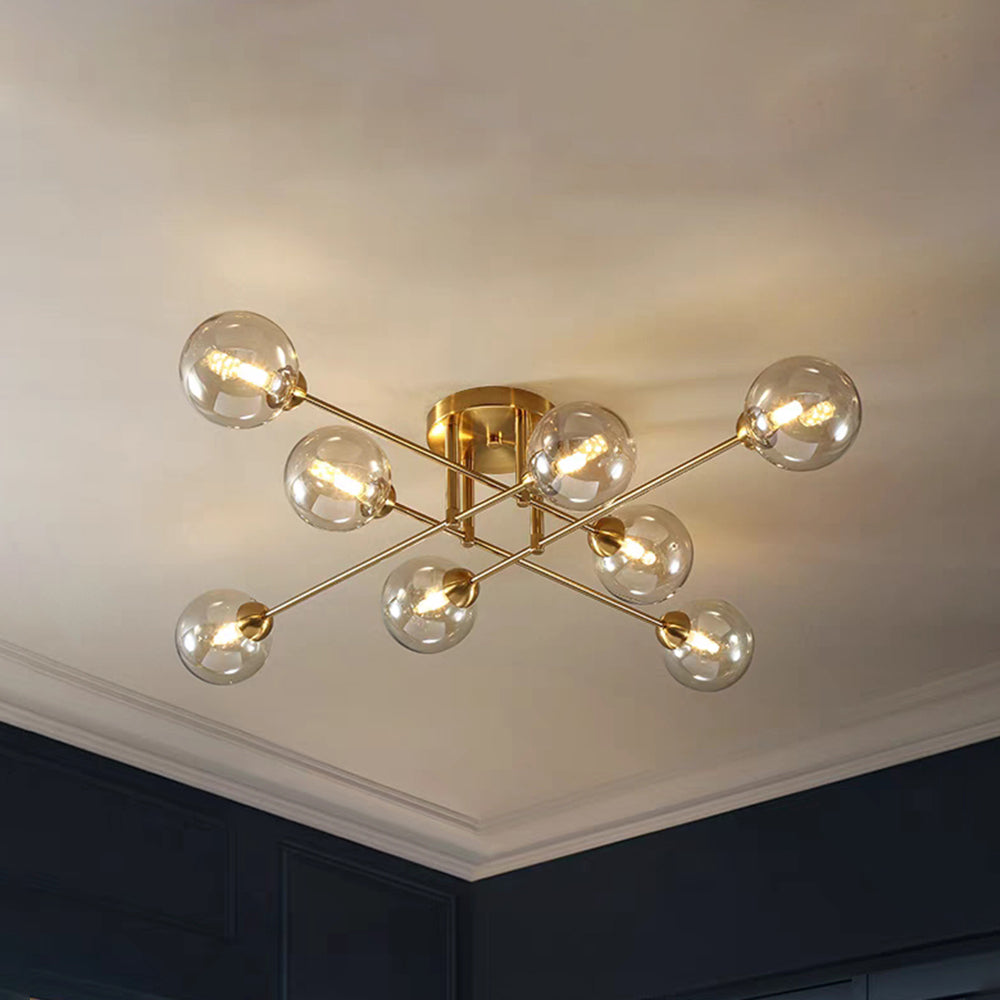 Eight cognac globes glow on the all-gold Clérachic sputnik chandelier, set against a white cornice above navy cabinetry.