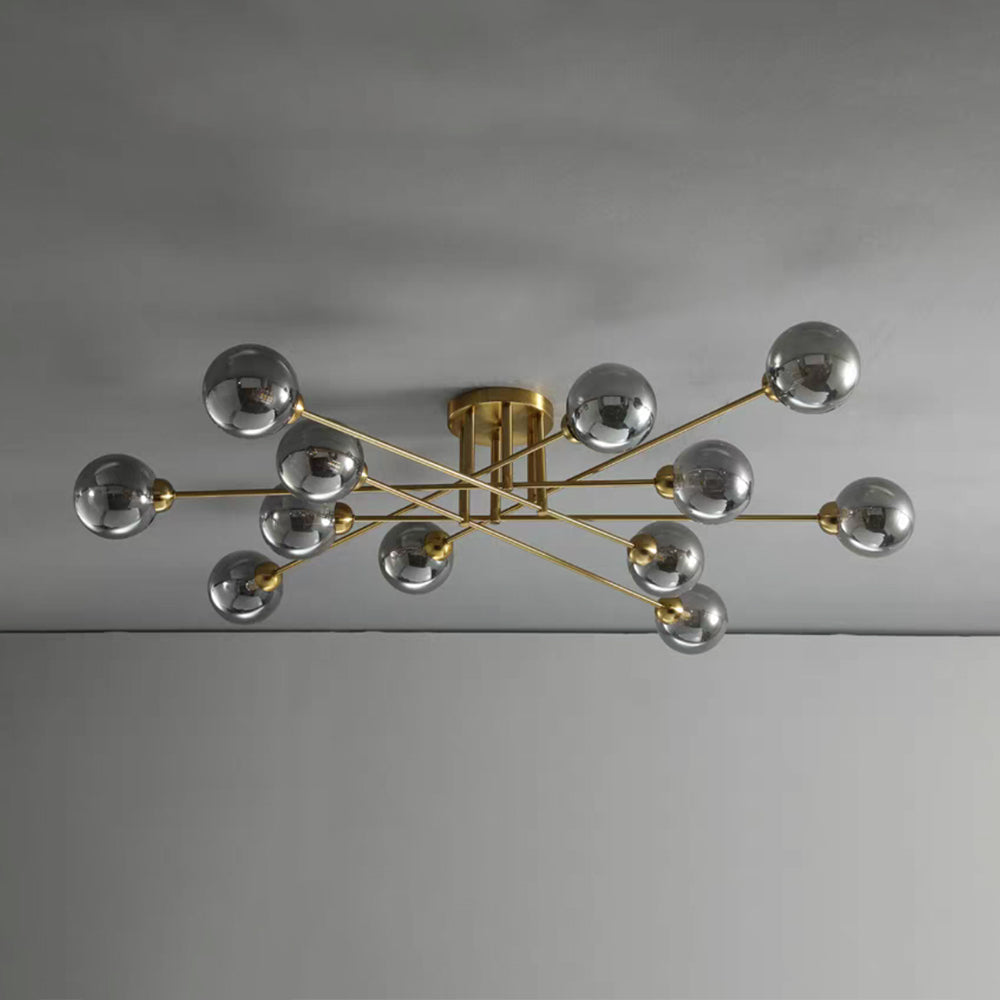 Twelve grey smoked globes on the gold Clérachic sputnik chandelier, its longest rods reaching across a grey ceiling.