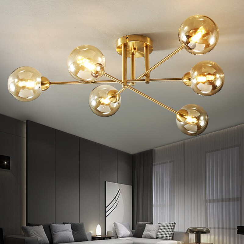 Clérachic sputnik chandelier lighting a grey living room, six cognac globes on gold arms above a sectional sofa.