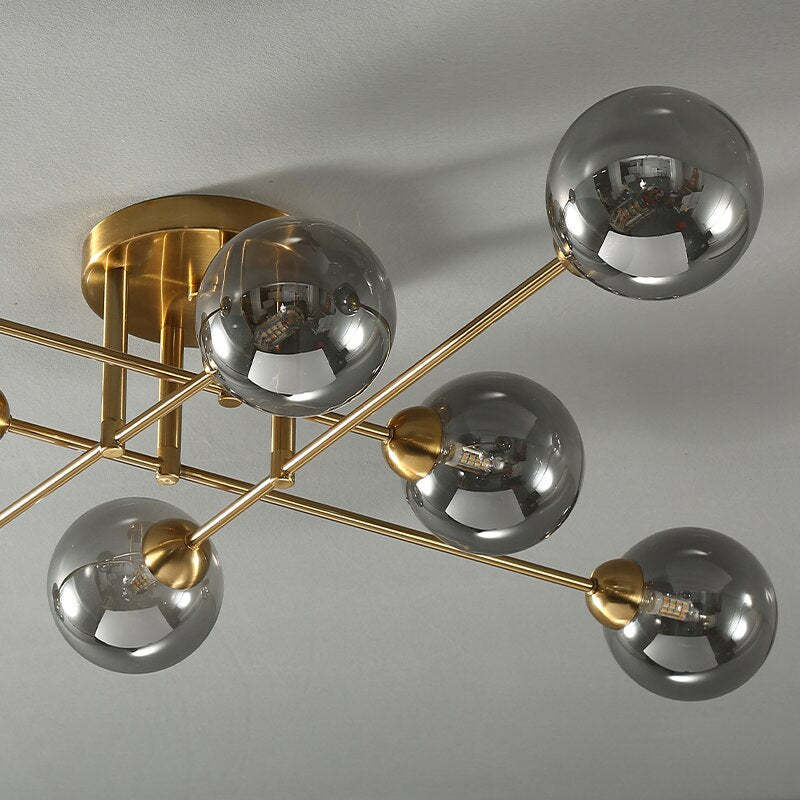 Detail of the Clérachic sputnik chandelier's gold canopy, with grey smoked globes and their G9 lamps reflected in the glass.