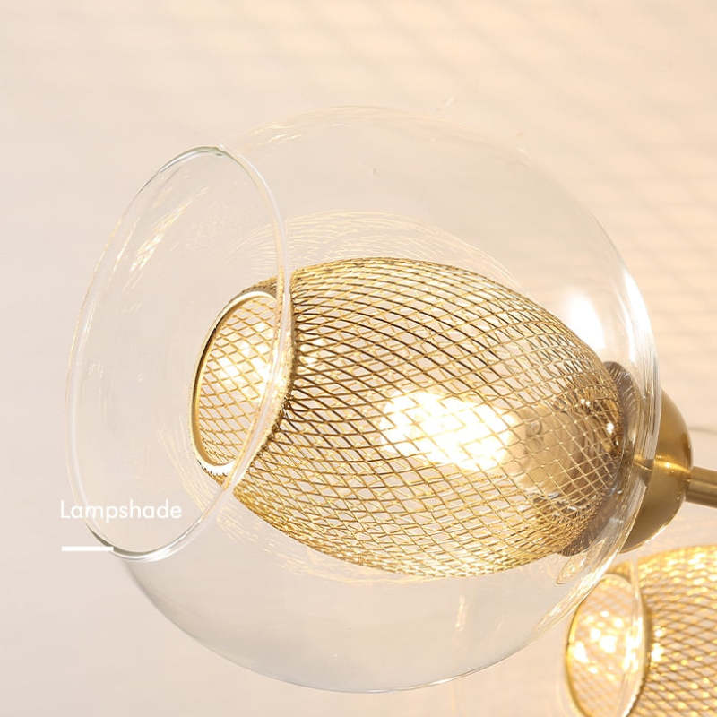 Macro of a single Clérachic sputnik chandelier shade, a fine gold wire mesh sleeve sitting inside the clear glass globe.