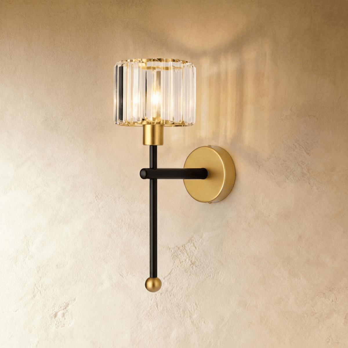 Clérachic wall lamp with a clear ribbed glass drum shade on a black stem and brass backplate, lit against a limewash wall.