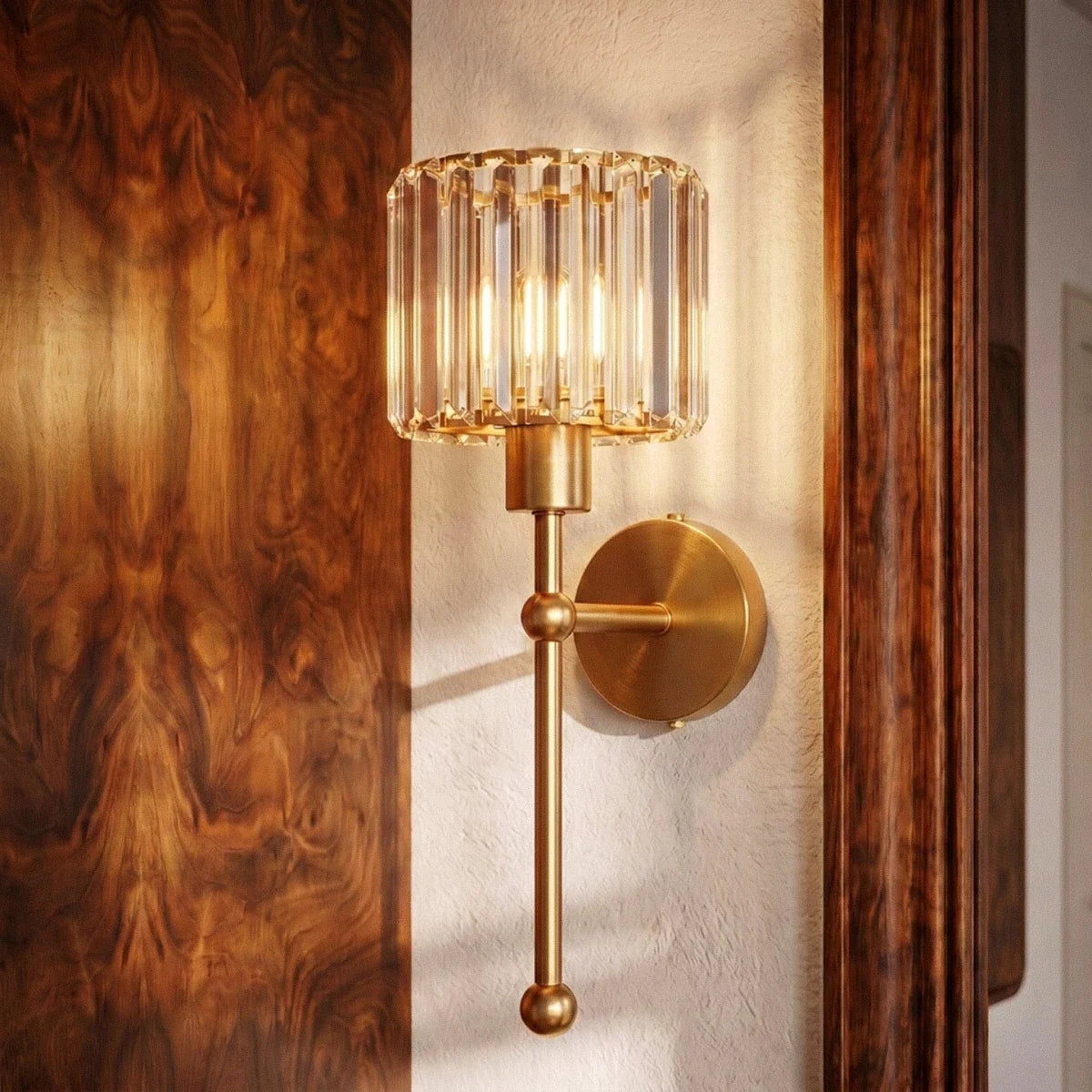 Clérachic brushed brass wall lamp with a ribbed glass shade, glowing beside walnut panelling and a white plaster wall.