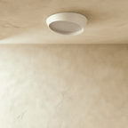 Clérachic round white ceiling light switched off, showing the angled iron rim and the frosted diffuser against a limewash ceiling.