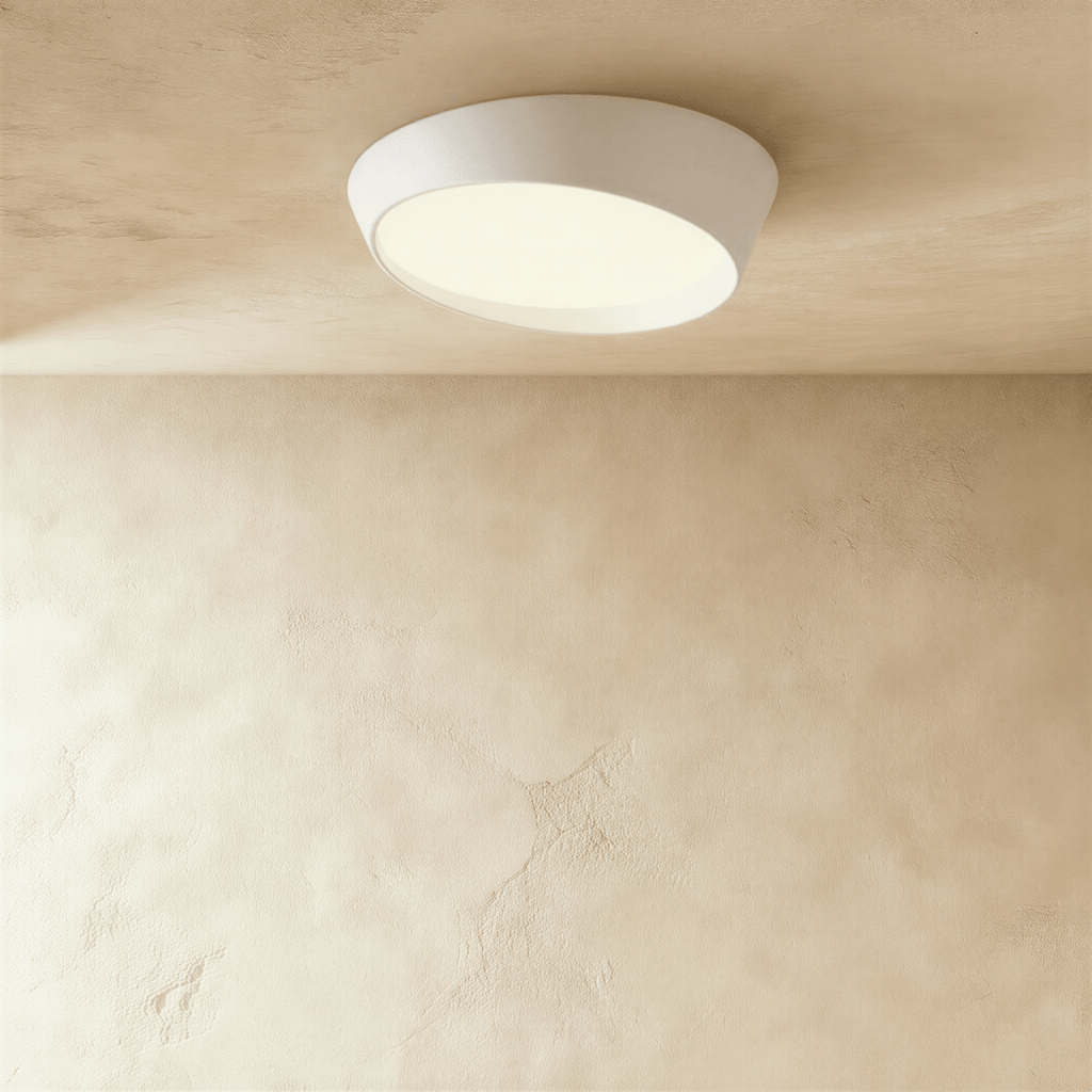 Clérachic larger white round ceiling light with an angled iron body and a softly lit frosted diffuser on a limewash ceiling.