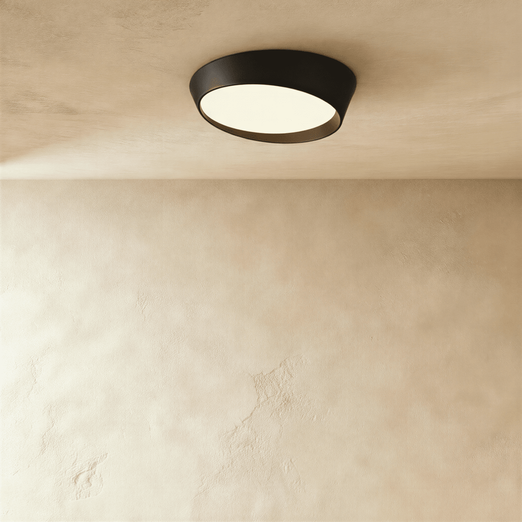Clérachic round ceiling light with a matte black iron rim and a warm-lit frosted diffuser on a limewash ceiling.