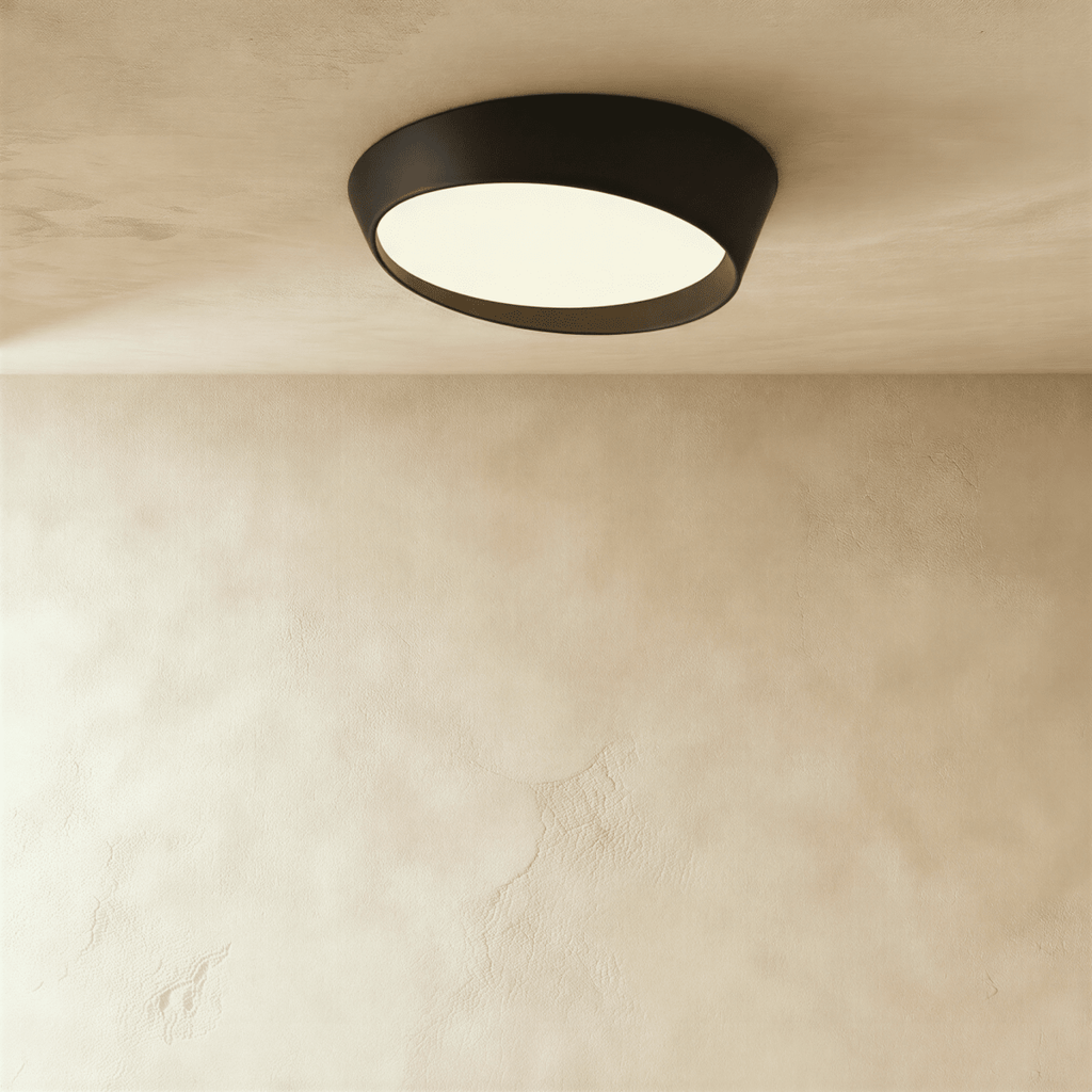 Clérachic wide black round ceiling light with a tilted frosted acrylic diffuser and a deep matte iron rim on a limewash ceiling.