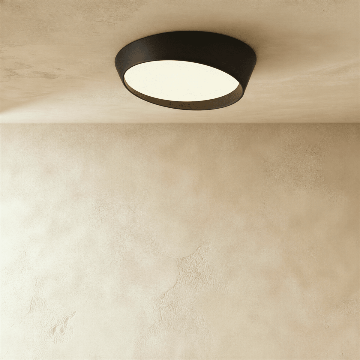 Clérachic wide black round ceiling light with a tilted frosted acrylic diffuser and a deep matte iron rim on a limewash ceiling.