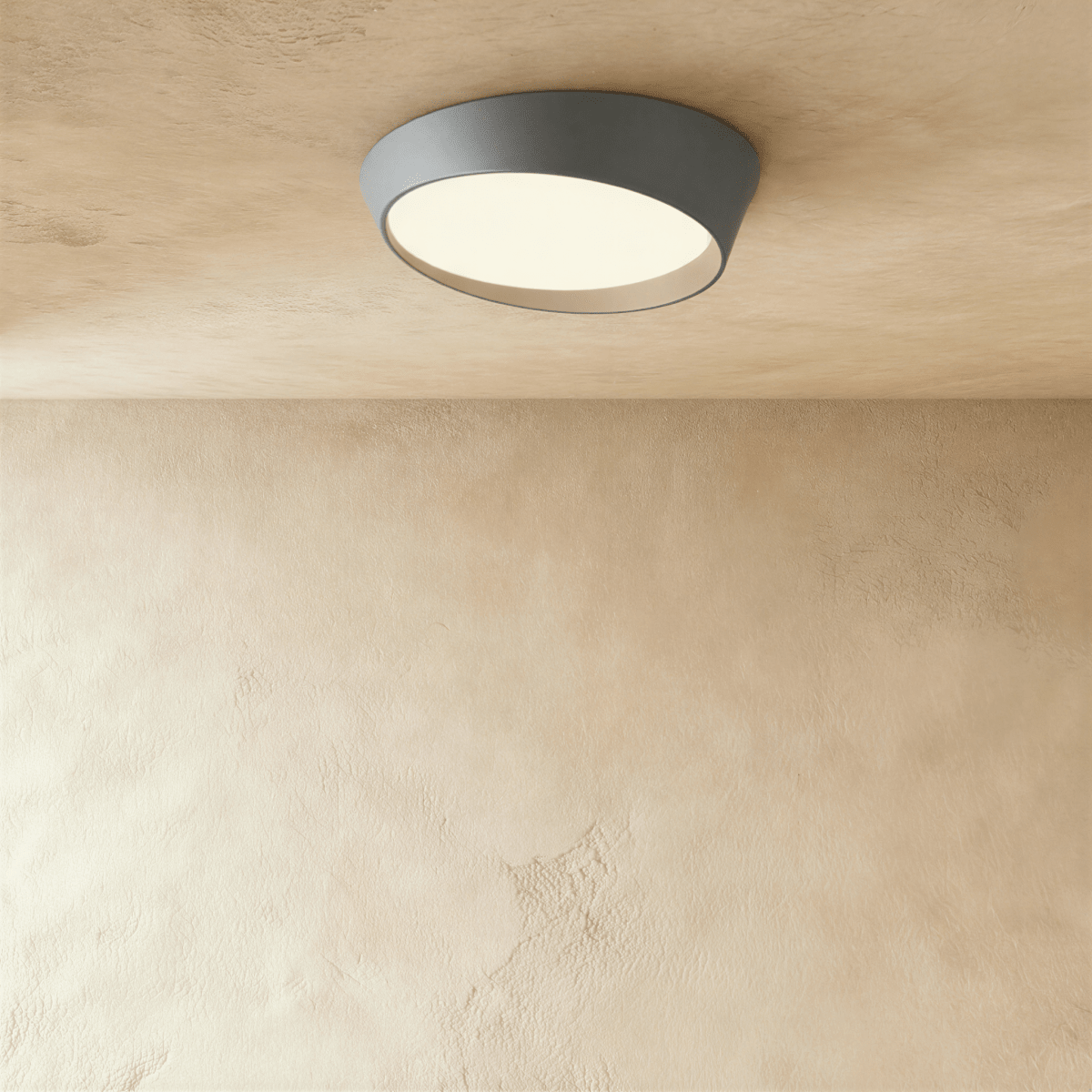 Clérachic grey low-profile ceiling light with an angled iron rim and a softly glowing frosted diffuser on a limewash ceiling.