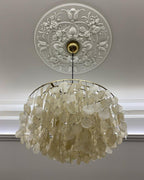 Looking up at a Clérachic shell chandelier hung from a carved white ceiling rose, its discs in warm cream.