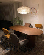 Clérachic shell chandelier glowing above an oval walnut table, with mustard chairs and a patterned rug beneath.