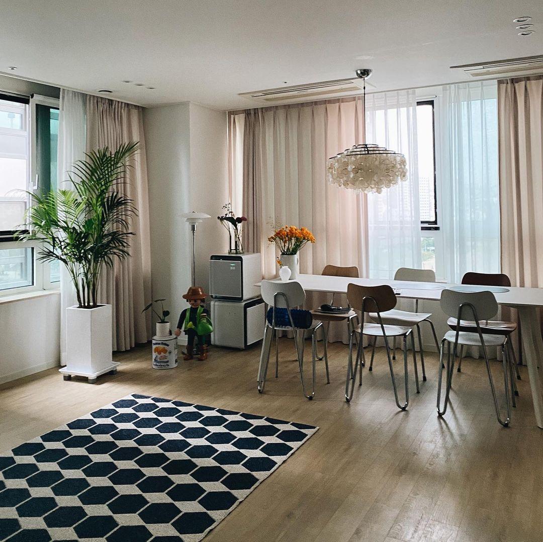 Small Clérachic shell chandelier far across a bright dining room with a blue hexagon rug, a tall palm and white table.