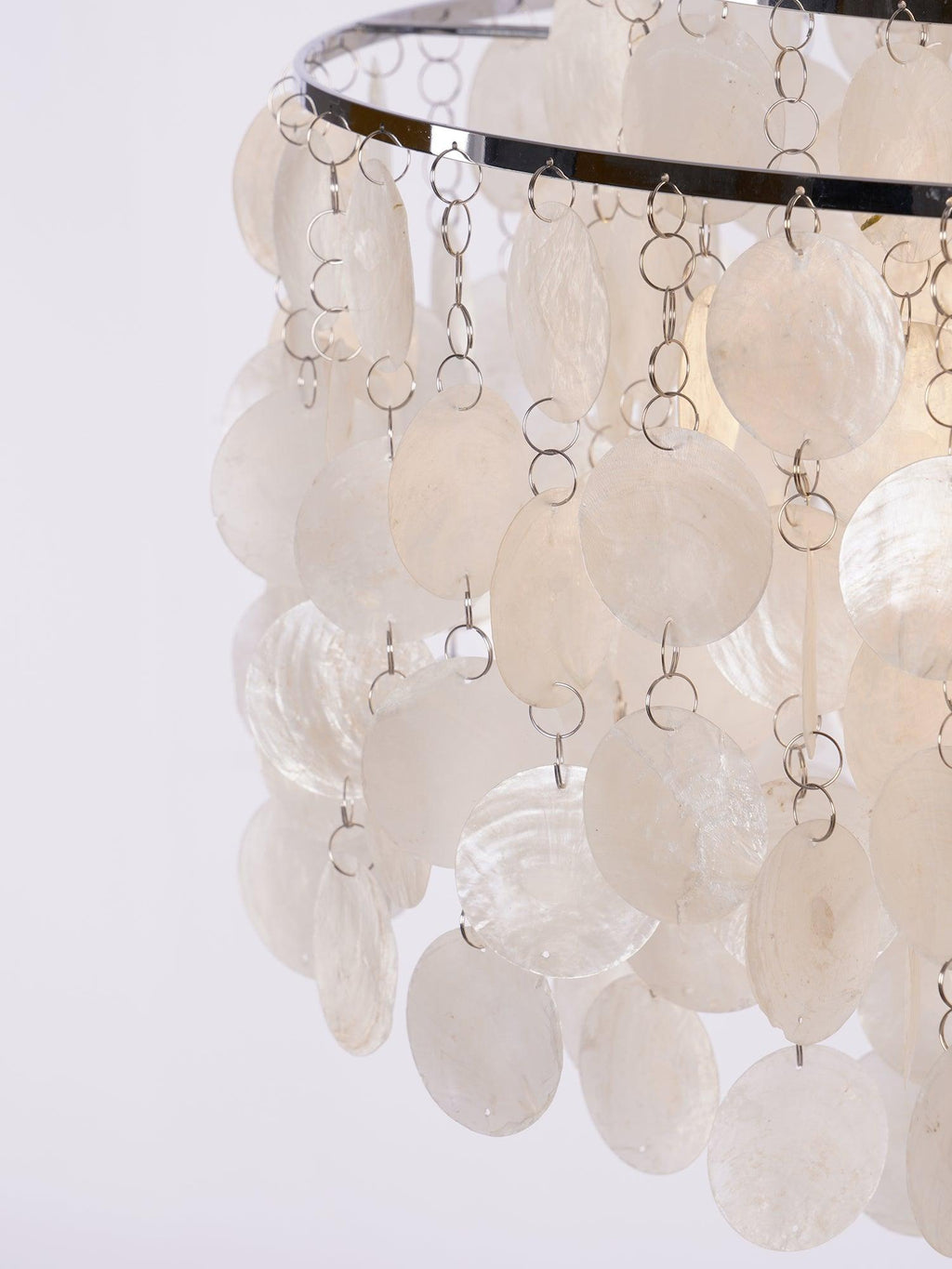 Close view of white shell discs on fine metal rings below a chrome hoop on this Clérachic chandelier.