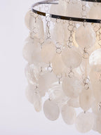 Close view of white shell discs on fine metal rings below a chrome hoop on this Clérachic chandelier.