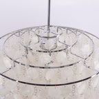 Inside the crown of this Clérachic chandelier, three concentric chrome rings with shell discs hanging on small links.