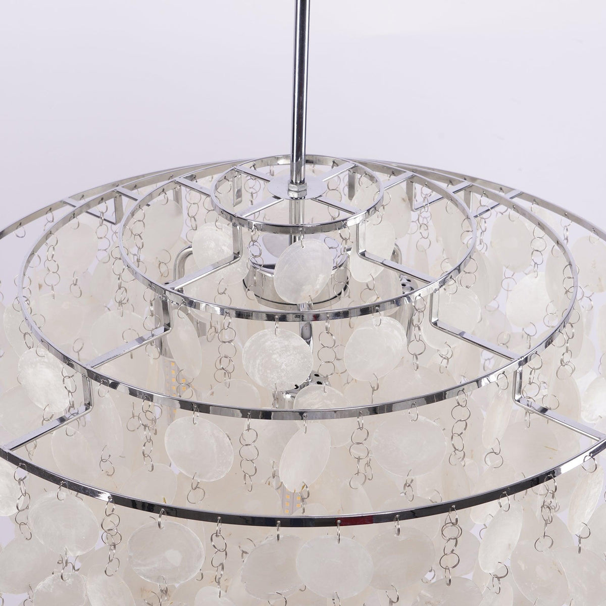 Inside the crown of this Clérachic chandelier, three concentric chrome rings with shell discs hanging on small links.