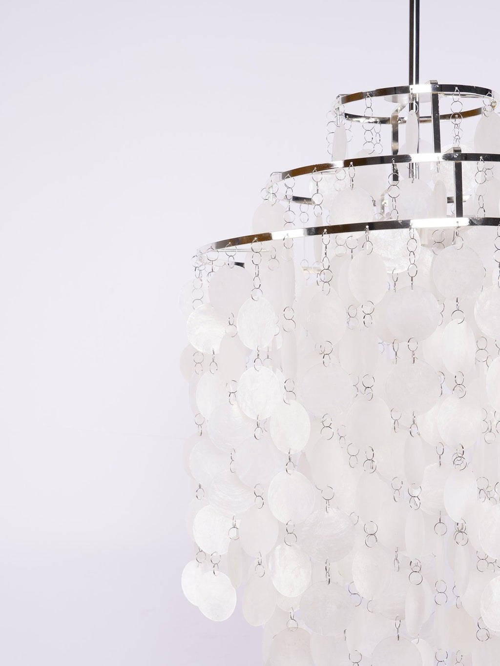 Side view of this Clérachic chandelier's chrome crown rings, with columns of white shell discs hanging in rows beneath.