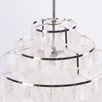 Close view of the chrome frame and a bulb inside this Clérachic shell chandelier, seen between white discs.