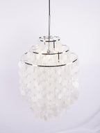 Narrow three-tier Clérachic shell chandelier with chrome rings, hung from a black cable against a pale lilac backdrop.