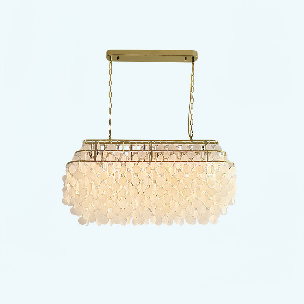 Rectangular Clérachic shell chandelier with a gold bar and chains, lit warm, on a pale backdrop.