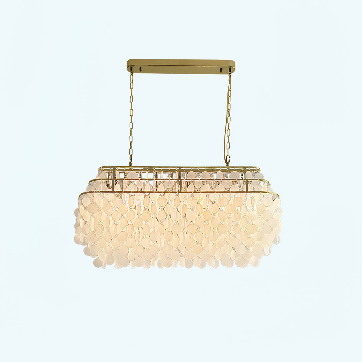 Rectangular Clérachic shell chandelier with a gold bar and chains, lit warm, on a pale backdrop.