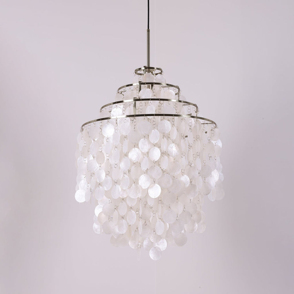 Three-tier chrome-ringed Clérachic shell chandelier, unlit, on a pale lilac backdrop with a black cable.
