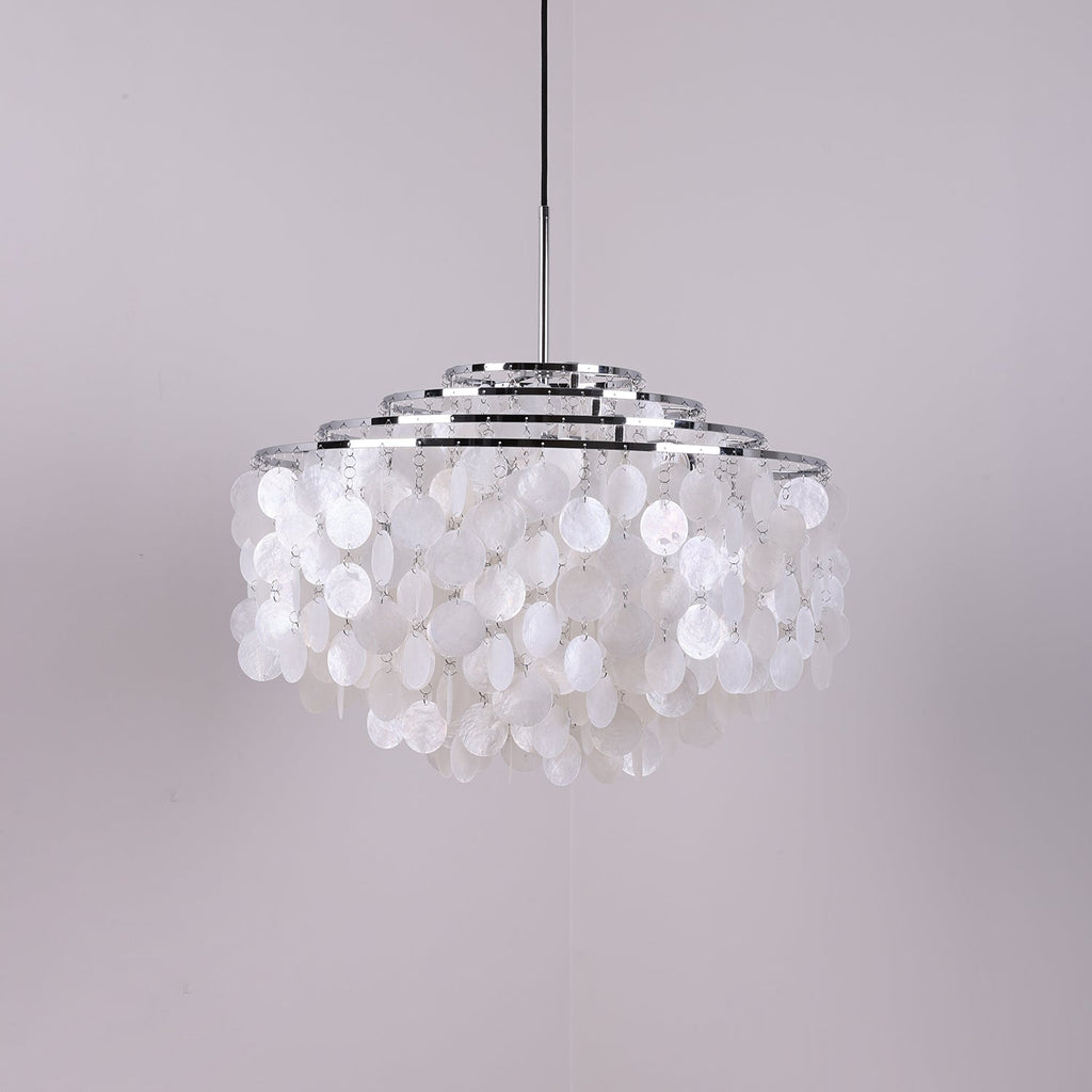 Wide chrome-ringed Clérachic shell chandelier, unlit, with white discs on a soft grey-lilac backdrop.