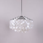Chrome-ringed Clérachic shell chandelier on a grey-lilac backdrop, discs hanging in rounded layers below the rings.