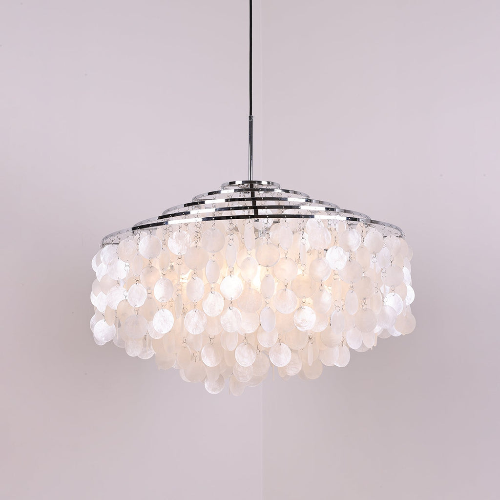 Clérachic shell chandelier with chrome rings, softly lit, its discs glowing pale white on a lilac backdrop.