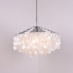 Clérachic shell chandelier with chrome rings, softly lit, its discs glowing pale white on a lilac backdrop.
