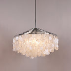 Lit Clérachic shell chandelier with a wide chrome crown, discs glowing warm and the bulbs faintly visible within.