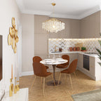 Gold-ringed Clérachic shell chandelier over a small round table in a kitchen with taupe cabinets and rust-coloured chairs.
