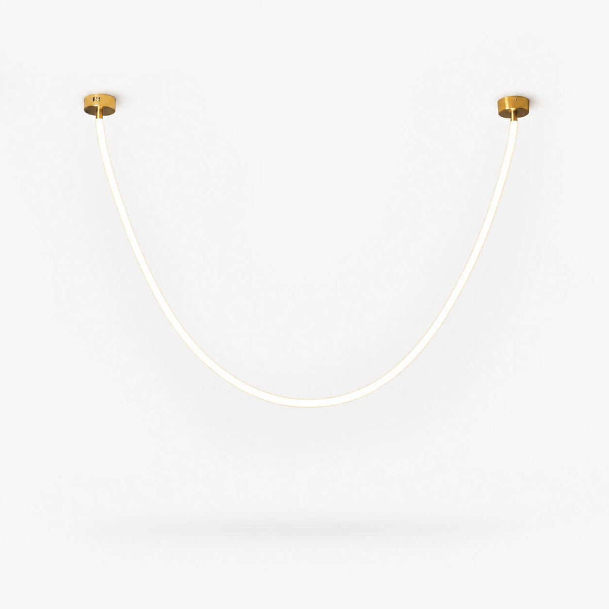 This Clérachic pendant light on a plain white backdrop, a slim glowing silicone tube curving in a deep U between two small gold ceiling plates.