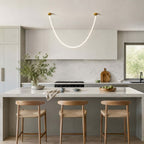 Above a pale kitchen island with woven-seat stools, this Clérachic pendant light arcs in a soft, even glow.
