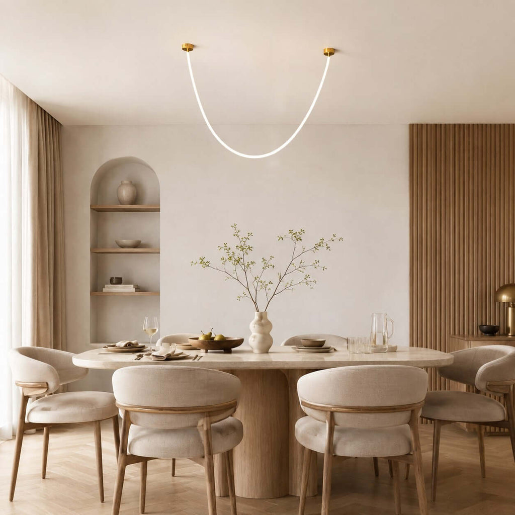 The U-shaped Clérachic pendant light hangs above a round dining table with cream chairs, a wood-slat wall behind.