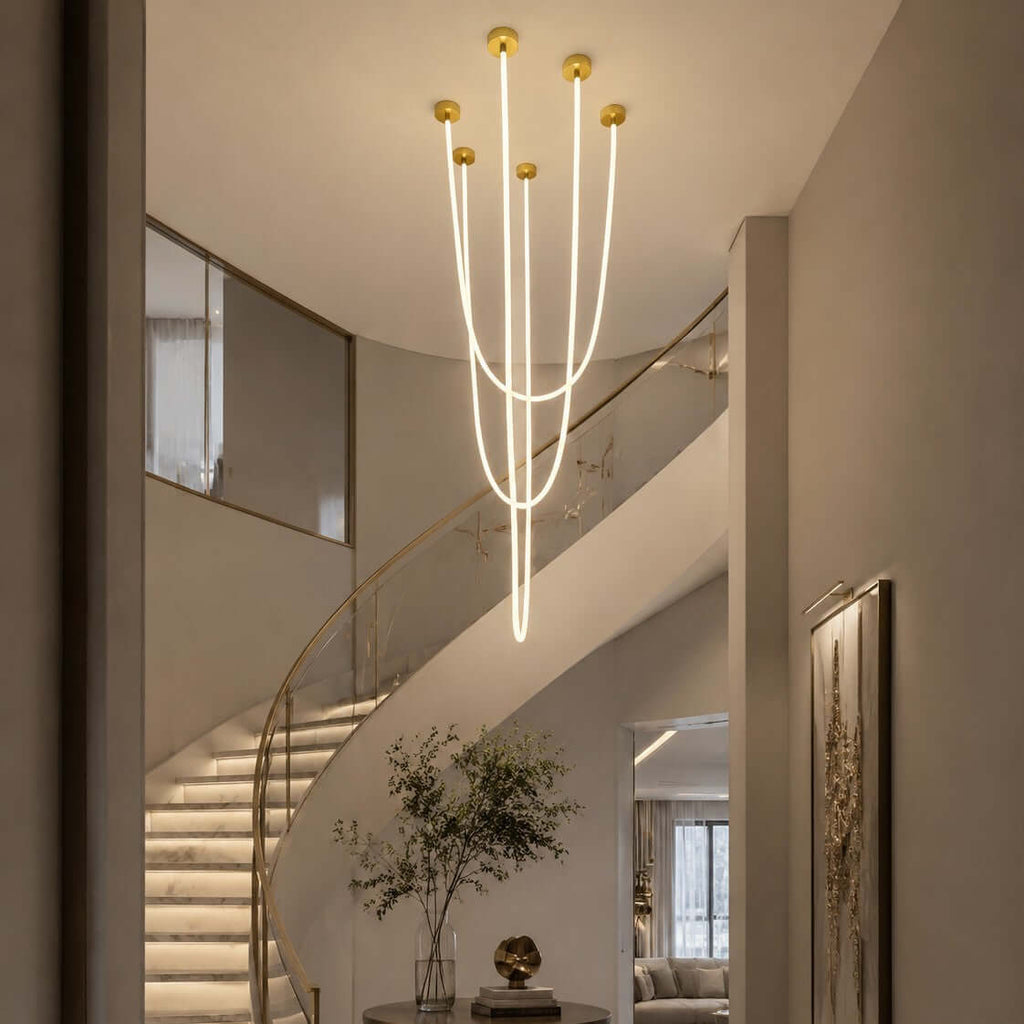 Beside a curved staircase with lit steps, this Clérachic pendant light drops its long glowing tubes at different heights.