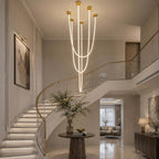 In a grand hall with a curving stair and a dark console, this Clérachic pendant light hangs its tubes in a long, tall cluster.