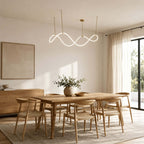 A Clérachic wave pendant above a light oak dining table with wooden chairs, in a room with sheer curtains and a balcony door.