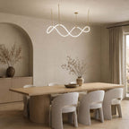 Lit Clérachic wave pendant in a dining room with an arched alcove, a long wooden table and pale grey chairs with rounded backs.