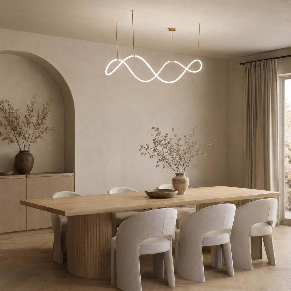 Lit Clérachic wave pendant in a dining room with an arched alcove, a long wooden table and pale grey chairs with rounded backs.