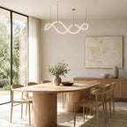 A Clérachic wave pendant hangs near a glass wall, above an oval oak table with wooden chairs and a ribbed sideboard.