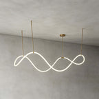 The Clérachic wave pendant lit and hung from three gold rods against a grey limewash wall, showing its continuous looping strip.