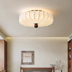 Clérachic flush-mount ceiling light glowing above a bedroom with a framed print over a wooden headboard and a branch in a vase.