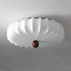 Unlit white pleated shade with a walnut-colour finial on this Clérachic ceiling light, seen from below against a grey ceiling.