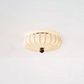 Lit Clérachic flush-mount ceiling light with a soft glow around its pleated shade, on a pale ceiling.