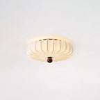 Lit Clérachic flush-mount ceiling light with a soft glow around its pleated shade, on a pale ceiling.